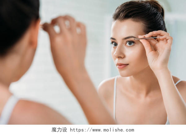 有吸引力的女孩矫正眉毛与镊子和看镜子在洗手间眉毛纹绣